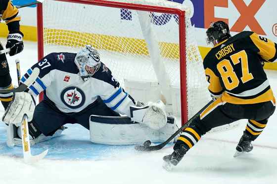 Winnipeg Jets goaltender Connor Hellebuyck (37) reaches to stop a shot by Pittsburgh Penguins Sidney Crosby (87) during the first period of an NHL hockey game, Tuesday in Pittsburgh. (Matt Freed / The Associated Press)