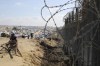 Palestinians displaced by the Israel air and ground offensive on the Gaza Strip sit next to the border fence with Egypt in Rafah, Wednesday, Jan. 24, 2024. THE CANADIAN PRESS/AP-Hatem Ali