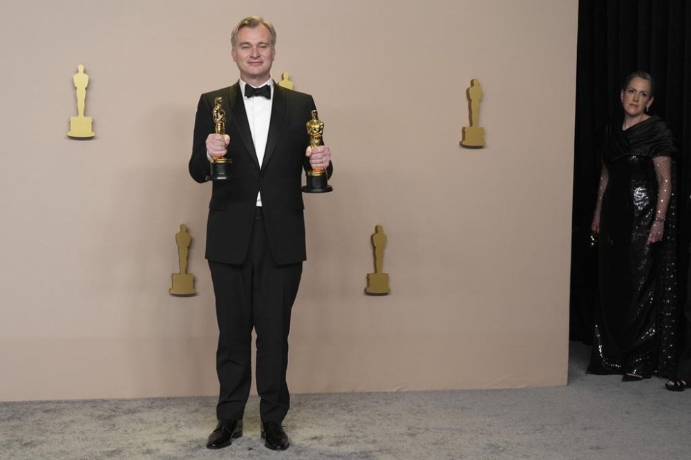 Christopher Nolan poses in the press room with the awards for best director and best picture for