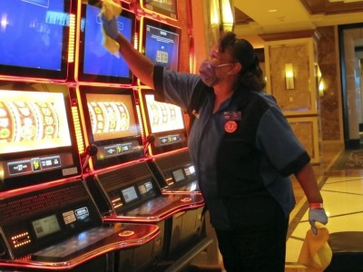 Jeorganna Barnes, a worker at Harrah's casino, on July 1, 2020, in Atlantic City, N.J., wipes slot machines with disinfectant as the casino prepared to reopen after 3 1/2 months of being shut down due to the coronavirus. On March 11, 2024, an independent report examining New Jersey's response to the pandemic said the state and nation were unprepared for it, adding the state is still underprepared for the next crisis. (AP Photo/Wayne Parry)