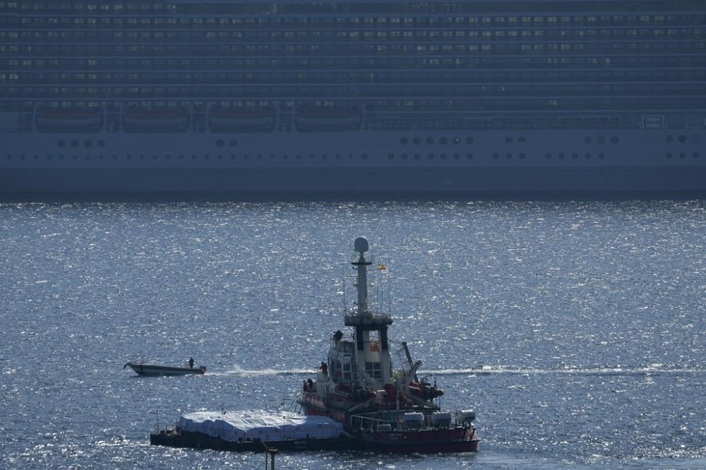The ship, left, belonging to the Open Arms aid group with aid on a platform ferry some 200 tonnes of rice and flour directly to Gaza, departs from the port from southern city of Larnaca, Cyprus, Tuesday, March 12, 2024. An aid ship loaded with some 200 tons of food set sail Tuesday from Cyprus to Gaza, the international charity behind the effort said. The shipment is a test for the opening of a sea corridor to supply aid to the territory, where starvation is spreading five months into the Israel-Hamas war. (AP Photo/Petros Karadjias)