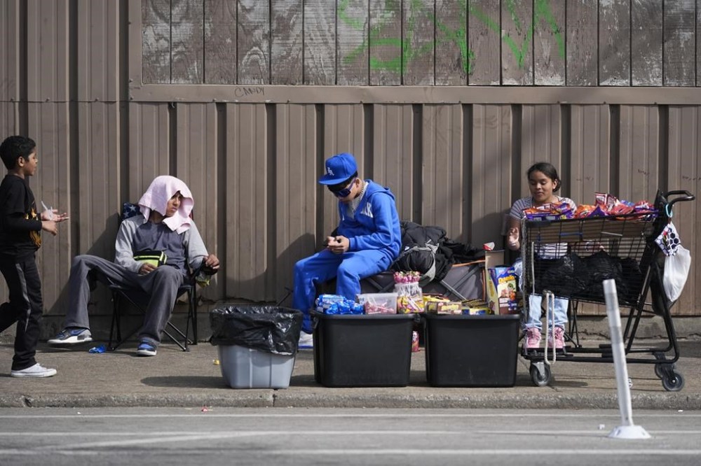 People hang around outside of a migrant shelter Wednesday, March 13, 2024, in the Pilsen neighborhood of Chicago. Multiple people living at the shelter for migrants have tested positive for measles since last week. A team from the Centers for Disease Control and Prevention is supporting local officials' response. (AP Photo/Erin Hooley)