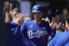 Los Angeles Dodgers' Freddie Freeman celebrates in the dugout after scoring on a single hit by teammate James Outman in the first inning of a spring training baseball game against the Texas Rangers on Saturday, March 9, 2024, in Phoenix. (AP Photo/Carolyn Kaster)
