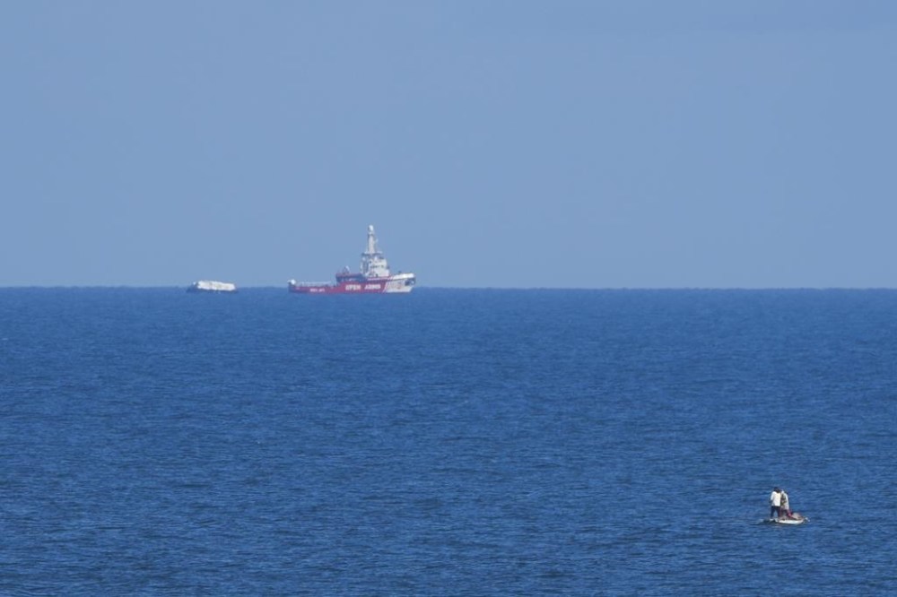 A ship belonging to the Open Arms aid group approaches the shores of Gaza towing a barge with 200 tons of humanitarian aid on Friday, March 15, 2024. The ship set sail Tuesday from Cyprus to inaugurate a sea route to get desperately needed aid into the war-wracked enclave, which is suffering a humanitarian crisis five months into the Israel-Hamas war. (AP Photo/Abdel Kareem Hana)