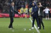 Fenerbahce's head coach Ismail Kartal, left, looks at small water plastic bottles thrown by Trabzonspor supporters from the stand during the Turkish Super Lig soccer match between Trabzonspor and Fenerbahce at the Senol Gunes stadium in Trabzon, Turkey, Sunday, March 17, 2024. Turkish top tier club Trabzonspor fans invaded the pitch following a home loss against Fenerbahce late Sunday, touching off violent scuffles between the fans and Fenerbahce players. (Huseyin Yavuz/Dia Images via AP)