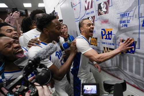 FILE - Pittsburgh guard Ishmael Leggett, right, places a decal on the bracket after an NCAA college basketball game against Wake Forest in the quarterfinal round of the Atlantic Coast Conference tournament March 14, 2024, in Washington. College hoops fans might want to think again before pinning their hopes of a perfect March Madness bracket on artificial intelligence. While the advancement of artificial intelligence into everyday life has made “AI” one of the buzziest phrases of the past year, its application in bracketology circles is not so new. (AP Photo/Susan Walsh, File)