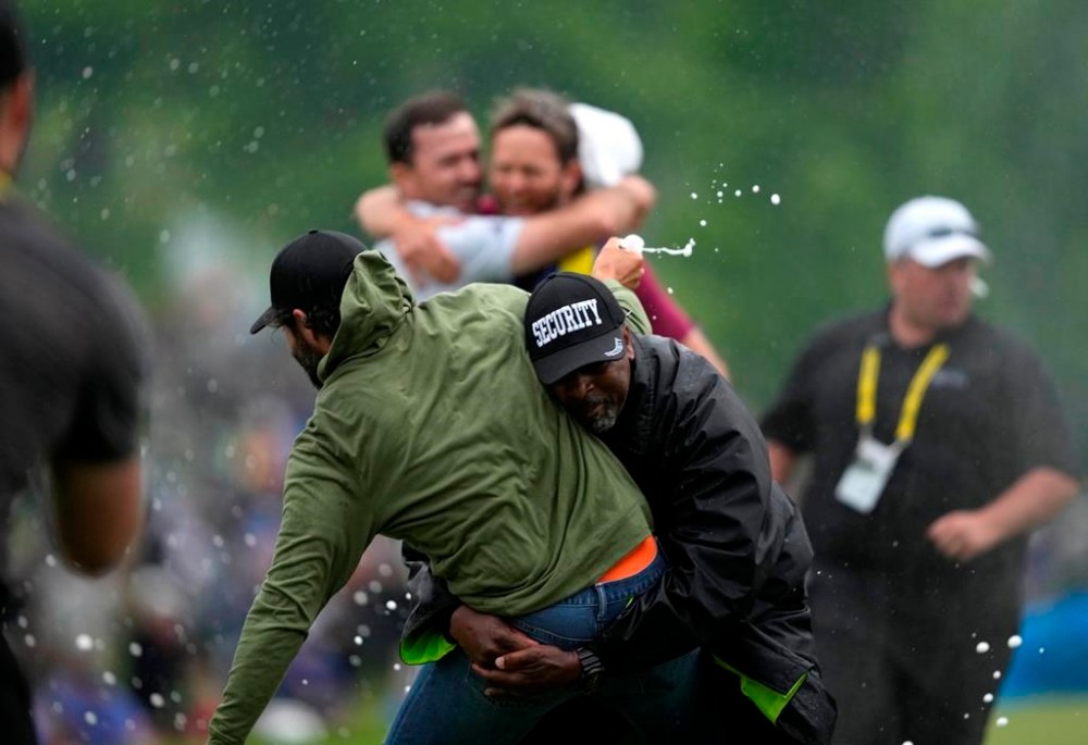 Canadian professional golfer Adam Hadwin, left, is stopped by a security guard while he tries to celebrate with Nick Taylor, of Canada, after Taylor won the Canadian Open championship on the fourth playoff hole against Tommy Fleetwood, of Southport, U.K., in Toronto on Sunday, June 11, 2023. Photographer Andrew Lahodynskyj is nominated in the sports photo category of the National Newspaper Awards for this image. THE CANADIAN PRESS/Andrew Lahodynskyj