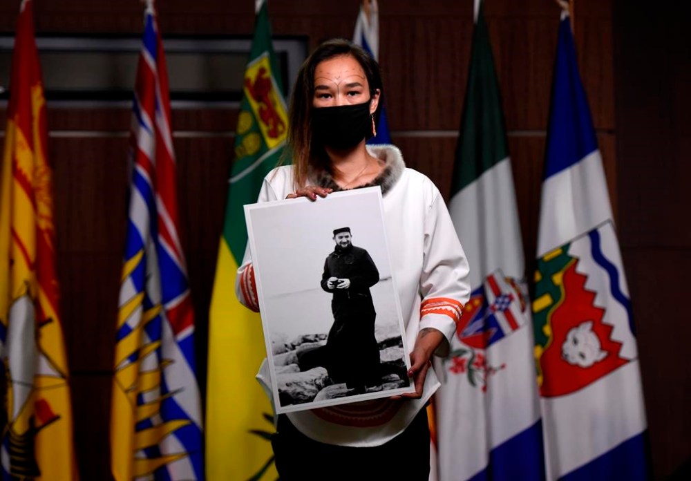 An independent review of a priest accused of sexually abusing children in Nunavut has found the Catholic order wasn’t aware of allegations when he returned to France just as RCMP began their investigations. Then-NDP MP Mumilaaq Qaqqaq holds a photo of Fr. Johannes Rivoire, who is wanted in Canada for abusing children in Nunavut but now resides in France, at a news conference on Parliament Hill in Ottawa, on Thursday, July 8, 2021. THE CANADIAN PRESS/Justin Tang