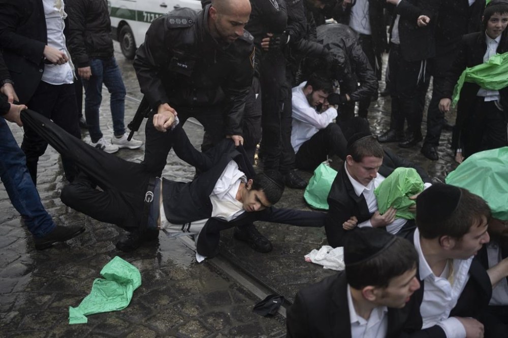 Israeli police officers scuffle with ultra-Orthodox Jewish men during a protest against a potential new draft law that could end their exemptions from military service in Jerusalem, Israel, Monday, March 18, 2024. (AP Photo/Leo Correa)
