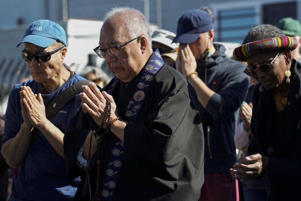 Buddhist faith leaders and community members pray during a