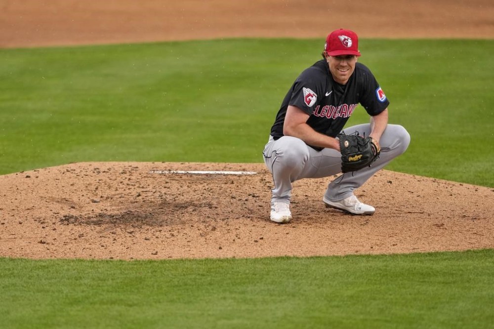 Cleveland Guardians pitcher Shane Bieber smiles after losing control of his pitch in the rain during the second inning of a spring training baseball game against the Oakland Athletics, Thursday, March 7, 2024, in Mesa, Ariz. (AP Photo/Matt York)