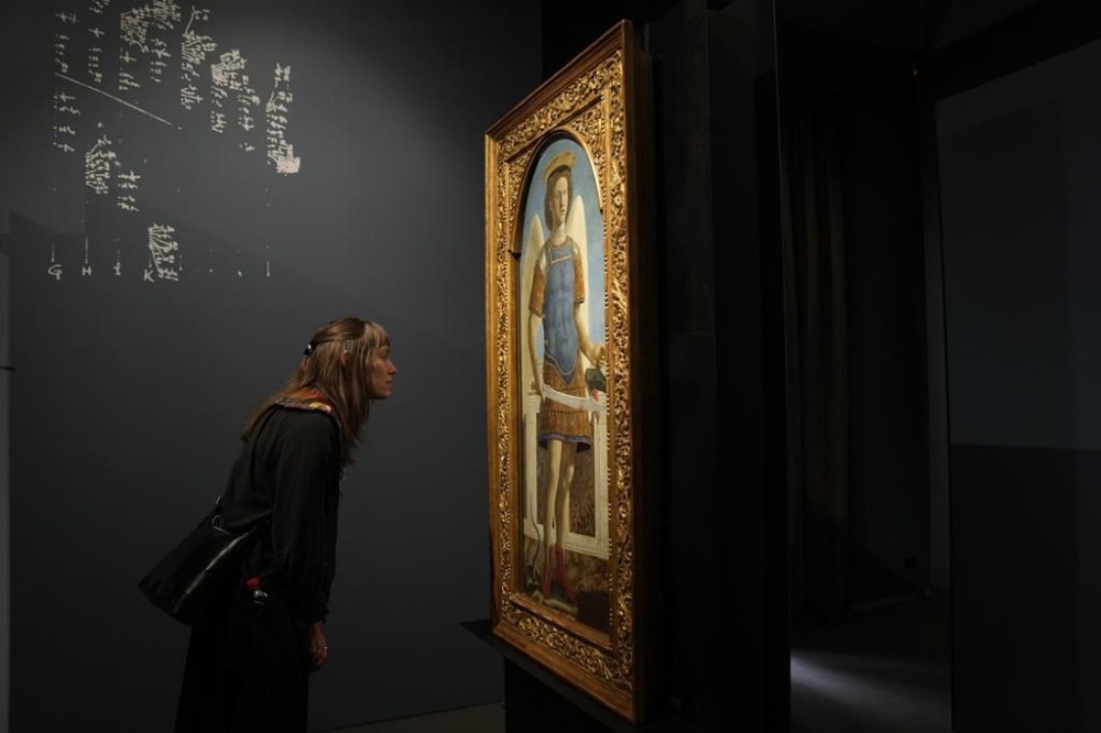 A visitor looks the Italian artist Piero della Francesca's St. Michael the Archangel paintings on the occasion of the inauguration of the exhibit