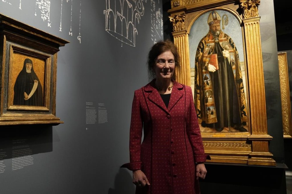 The exhibition curator Machtelt Bruggen Israels poses next to Italian artist Piero della Francesca's paintings on the occasion of the inauguration of the exhibit