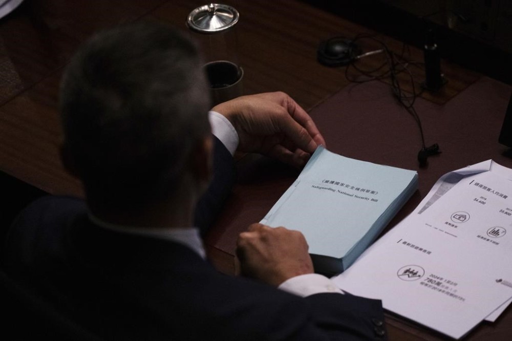 A lawmaker holds a copy of the proposed Safeguarding National Security Bill during the second reading of the Basic Law Article 23 legislation at the Legislative Council in Hong Kong, Tuesday, March 19, 2024. (AP Photo/Louise Delmotte)