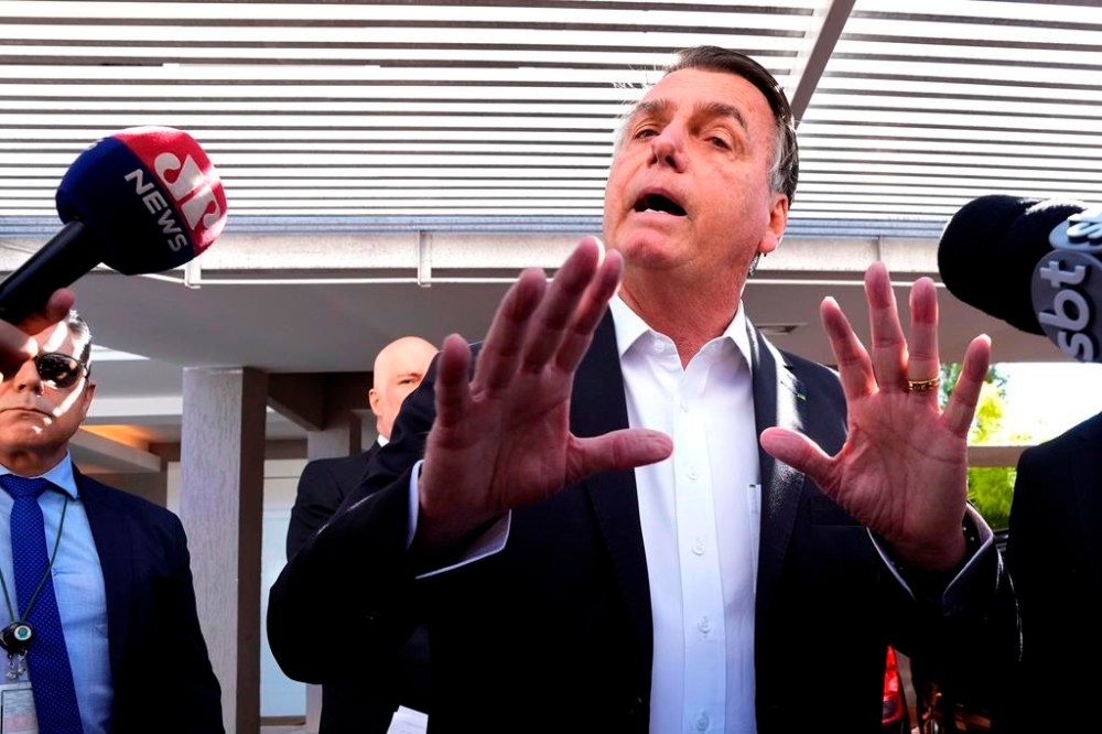 FILE - Former Brazilian President Jair Bolsonaro speaks to the press outside his home after Federal Police agents carried out a search and seizure warrant in Brasilia, Brazil, May 3, 2023. When asked about the search of Bolsonaro's home in Brasilia, the Federal Police press office gave a statement saying officers were carrying out searches and arrests related to the introduction of fraudulent data related to the COVID-19 vaccine into the nation's health system. (AP Photo/Eraldo Peres)