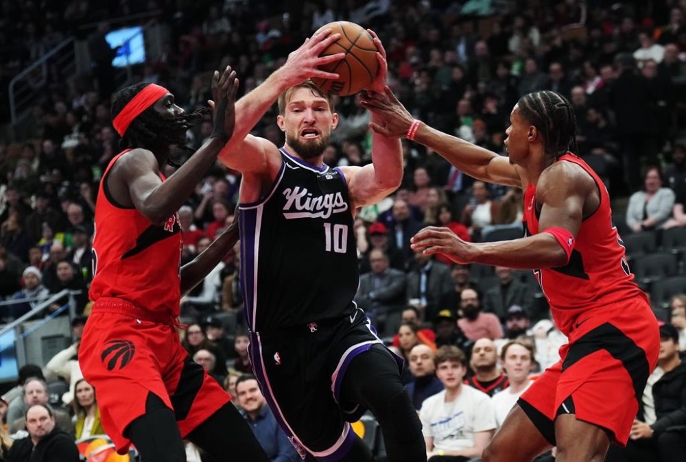 Sacramento Kings forward Domantas Sabonis (10) drives between Toronto Raptors forward Mouhamadou Gueye (left) and guard Jahmi'us Ramsey (right) during second half NBA basketball action in Toronto on Wednesday, March 20, 2024. THE CANADIAN PRESS/Nathan Denette