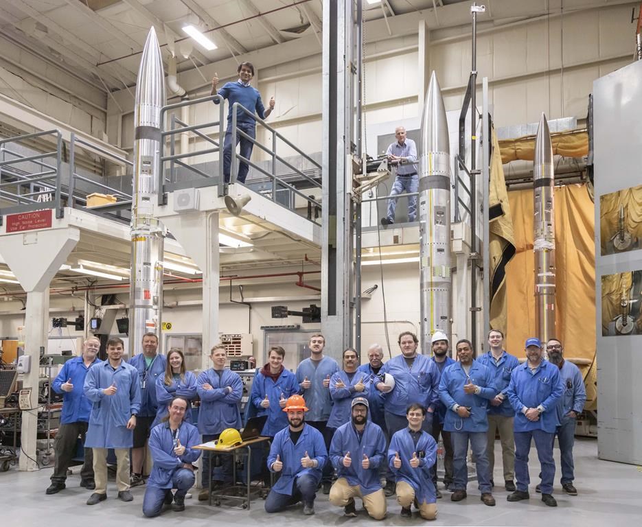 This photo provided by NASA shows three APEP rockets at NASA Wallops Flight Facility on Wallops Island, Va., on Feb. 21, 2024, with Mission Principal Investigator Dr. Barjatya, top left, and NASA Mission Manager Jay Scott, top right, and Embry-Riddle Aeronautical University and NASA personnel. During the April 8, 2024 total solar eclipse, the rockets will blast off with science instruments into the electrically charged portion of the atmosphere near the edge of space known as the ionosphere. (Berit Bland/NASA via AP)