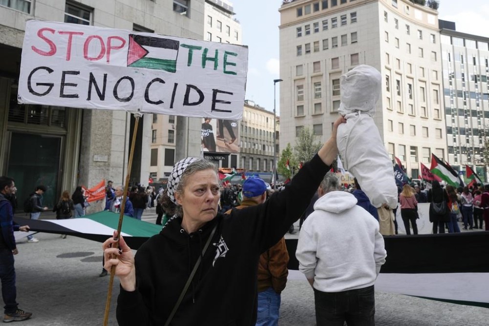 A demonstrator holds a banner reading 'Stop the genocide' during a rally in solidarity with Palestinians, in Milan, Italy, Saturday, March 23, 2024. (AP Photo/Luca Bruno)