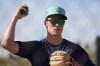 FILE - Seattle Mariners starting pitcher Bryan Woo warms up during spring training baseball workouts, Feb. 15, 2024, in Peoria, Ariz. The Mariners will start the season with Woo on the 15-day injured list due to inflammation in his right elbow. (AP Photo/Lindsey Wasson, File)