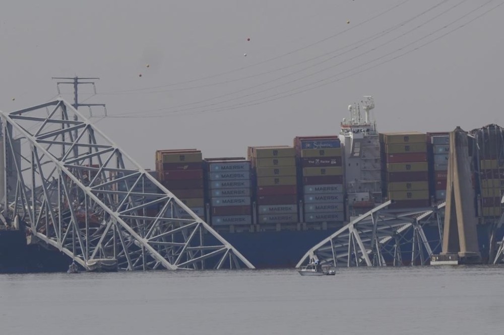 A container rests against wreckage of the Francis Scott Key Bridge on Tuesday, March 26, 2024, as seen from Sparrows Point, Md. The ship rammed into the major bridge in Baltimore early Tuesday, causing it to collapse in a matter of seconds and creating a terrifying scene as several vehicles plunged into the chilly river below. (AP Photo/Matt Rourke)
