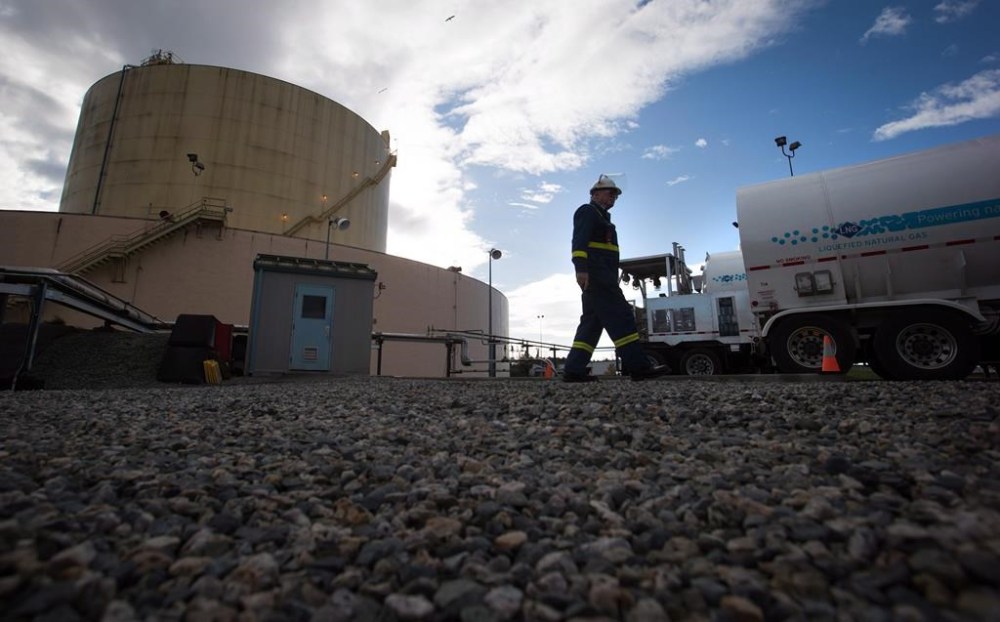 A FortisBC employee walks past a storage tank and delivery trucks at the existing FortisBC Tilbury LNG facility before the groundbreaking for an expansion project in Delta, B.C., on Tuesday, Oct. 21, 2014. An environmental group is suing British Columbia natural gas utility FortisBC, accusing it of