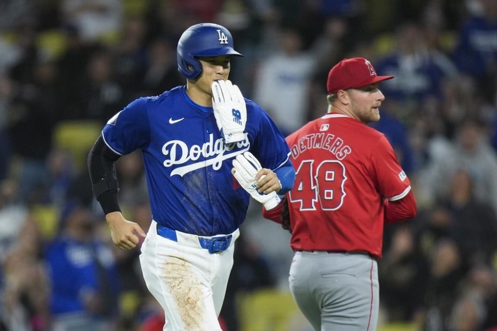 Los Angeles Dodgers' Shohei Ohtani, left, smiles as he heads toward the dugout past Los Angeles Angels starting pitcher Reid Detmers after the fifth inning of a spring training baseball game Monday, March 25, 2024, in Los Angeles. (AP Photo/Jae C. Hong)
