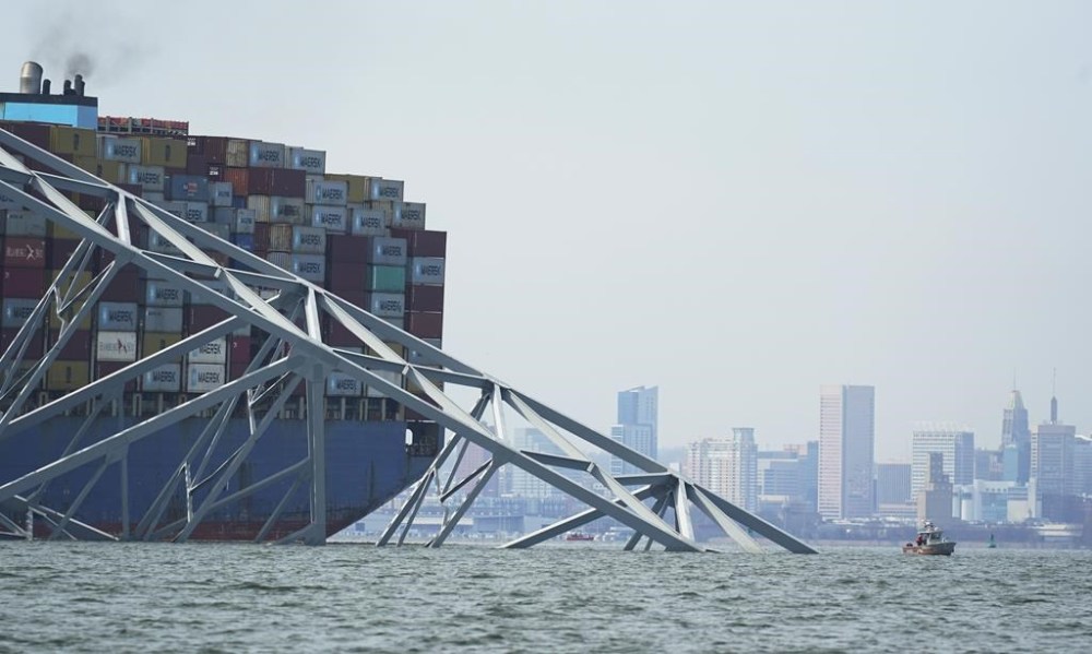 The Baltimore city skyline is visible behind a cargo ship that is stuck under the part of the structure of the Francis Scott Key Bridge after the ship hit the bridge Tuesday March 26, 2024, in Baltimore, Md. (AP Photo/Steve Helber)