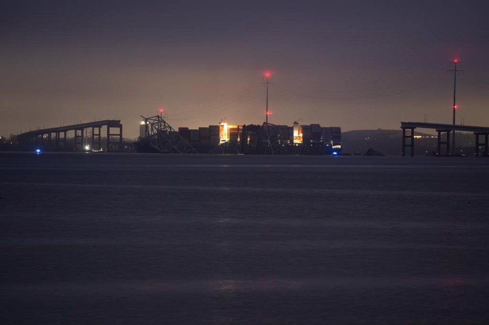 A container ship rests against wreckage of the Francis Scott Key Bridge as dawn approaches on Wednesday, March 27, 2024, in Baltimore, Md. Recovery efforts resumed Wednesday for the construction workers who are presumed dead after the cargo ship hit a pillar of the bridge, causing the structure to collapse. (AP Photo/Matt Rourke)