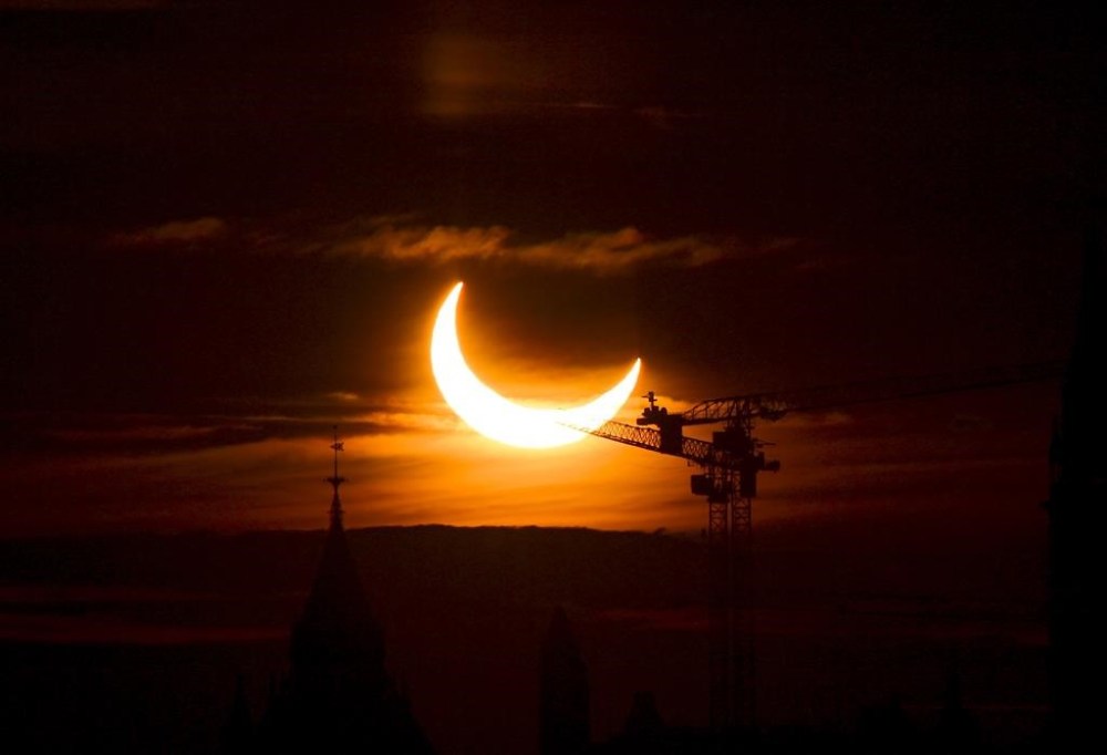 An annular solar eclipse rises over construction cranes and the Peace Tower on Parliament Hill in Ottawa on Thursday, June 10, 2021. THE CANADIAN PRESS/Sean Kilpatrick