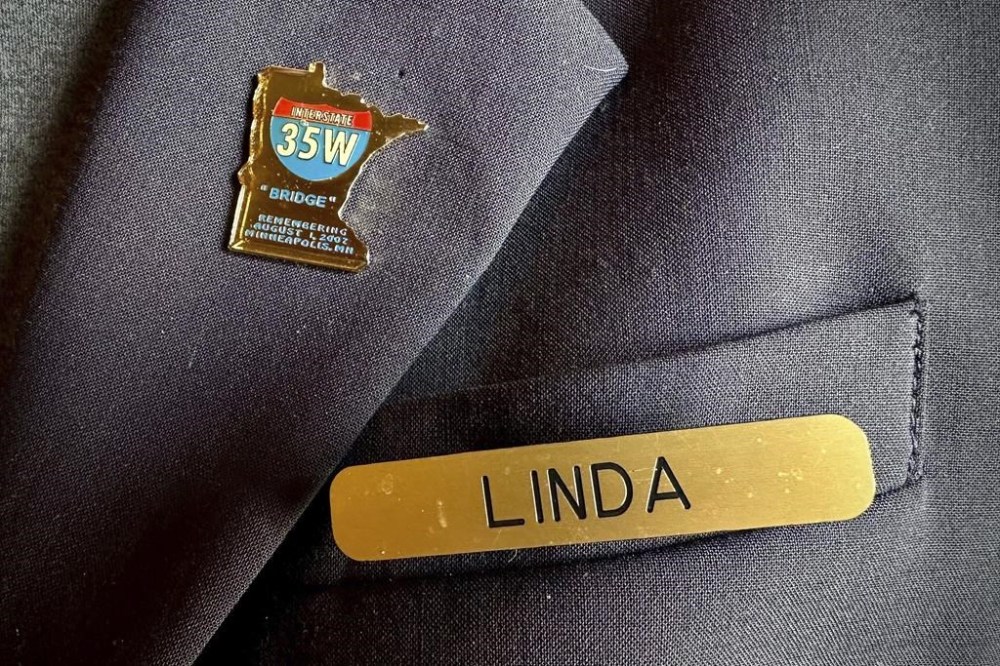 A gold pin in the shape of Minnesota – with the words