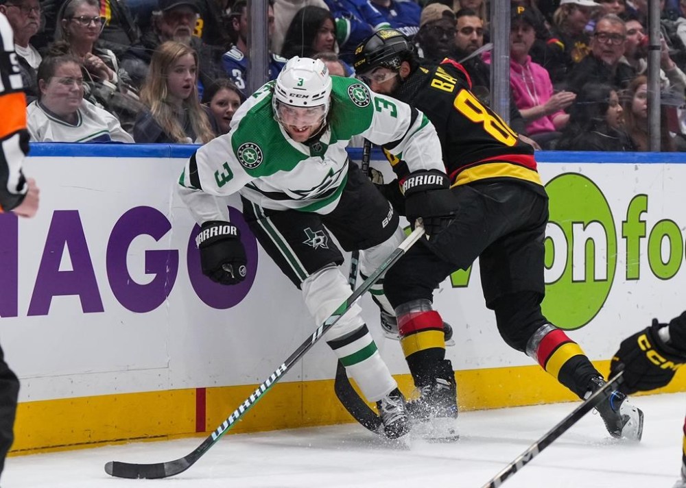 Dallas Stars' Chris Tanev (3) is checked by Vancouver Canucks' Arshdeep Bains (80) during the third period of an NHL hockey game in Vancouver, on Thursday, March 28, 2024. THE CANADIAN PRESS/Darryl Dyck