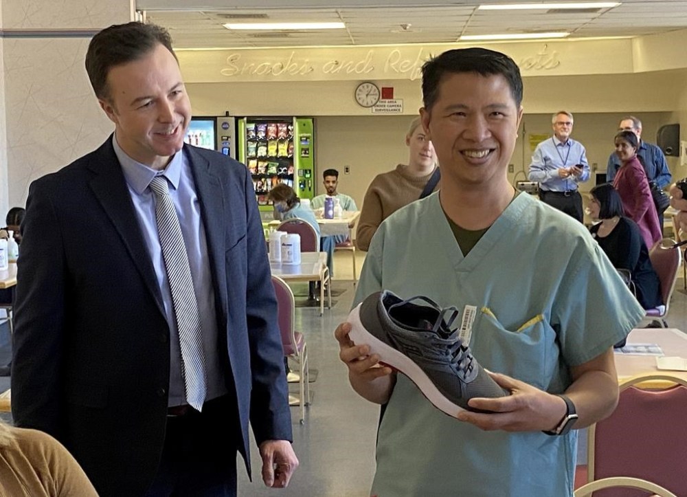 Manitoba Finance Minister Adrien Sala, left, gives a new pair of shoes to a health-care worker at the Victoria Hospital in Winnipeg, Thursday, March 28, 2024.The provincial budget will be released next week. THE CANADIAN PRESS/Steve Lambert