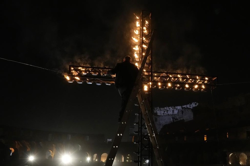 A worker lights candles on a cross at the Colosseum prior to the start of a Via Crucis (Way of the Cross) torchlight procession on Good Friday, in Rome, Friday, March 29, 2024. (AP Photo/Gregorio Borgia)