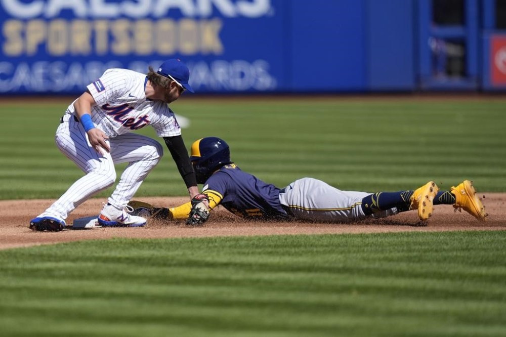 Milwaukee Brewers' Jackson Chourio, right, slides past New York Mets' Jeff McNeil to steal second base during the first inning of a baseball game Friday, March 29, 2024, in New York. (AP Photo/Frank Franklin II)