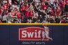 Washington Nationals' Lane Thomas scales the wall as fans catch a two-run home run by Cincinnati Reds' Luke Maile during the fifth inning of a baseball game in Cincinnati, Saturday, March 30, 2024. (AP Photo/Aaron Doster)