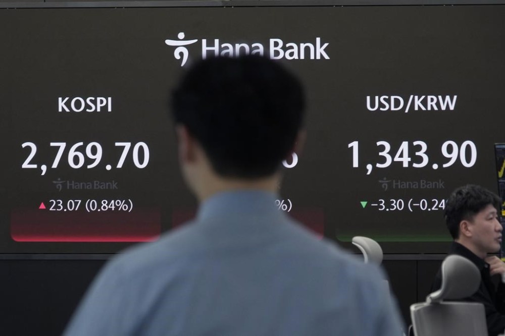 A currency trader passes by the screen showing the Korea Composite Stock Price Index (KOSPI), left, and the foreign exchange rate between U.S. dollar and South Korean won at the foreign exchange dealing room of the KEB Hana Bank headquarters in Seoul, South Korea, Monday, April 1, 2024. Asian shares were mixed Monday, with Shanghai gaining 1% after surveys showed improvements in manufacturing conditions in China.(AP Photo/Ahn Young-joon)