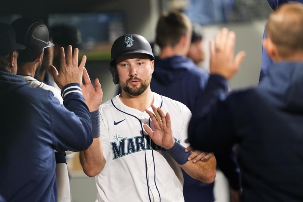 Seattle Mariners' Cal Raleigh is greeted in the dugout after scoring on a bases-loaded walk of Luis Urías by Cleveland Guardians relief pitcher Nick Sandlin during the fourth inning of a baseball game Monday, April 1, 2024, in Seattle. (AP Photo/Lindsey Wasson)