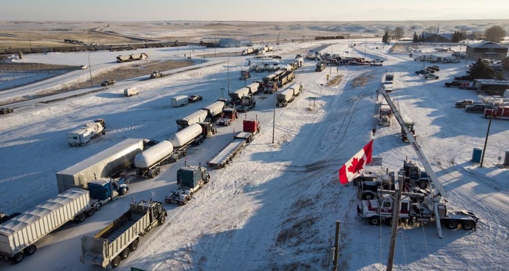 A truck convoy of anti-COVID-19 vaccine mandate demonstrators block the highway at the busy U.S. border crossing at Coutts, Alta., Wednesday, Feb. 2, 2022. Jury selection has started in a trial for three men charged in connection with the blockade. THE CANADIAN PRESS/Jeff McIntosh