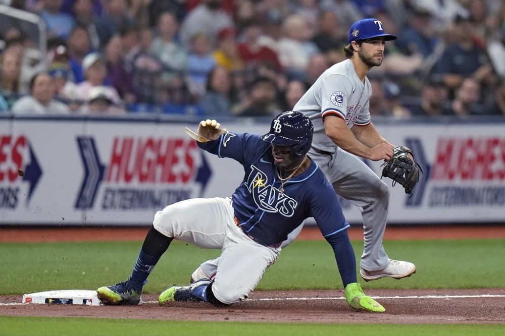 Tampa Bay Rays' Yandy Diaz slides into third base ahead of the throw to Texas Rangers third baseman Josh Smith on a single by Harold Ramirez during the third inning of a baseball game Tuesday, April 2, 2024, in St. Petersburg, Fla. (AP Photo/Chris O'Meara)