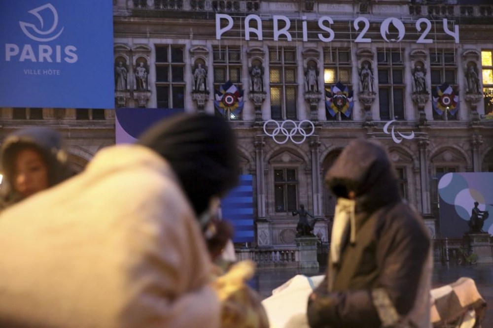 Migrants stand in front of the Paris City Hall, Wednesday, April 3, 2024. French police has removed about 50 migrants, including families with young children, from the Paris City Hall plaza as the capital prepares to mark 100 days to the start of the Olympic Games. (AP Photo/Nicolas Garriga)