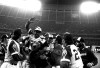 FILE - Atlanta Braves' Hank Aaron, top, is congratulated by teammates at home plate after hitting his 715th career home run in a game against the Los Angeles Dodgers in Atlanta, Monday night, April 8, 1974. Just in time for the 50-year anniversary of Hank Aaron's record 715th home run, Charlie Russo is making available video he shot of the homer. (AP Photo/Charles Knoblock, File)