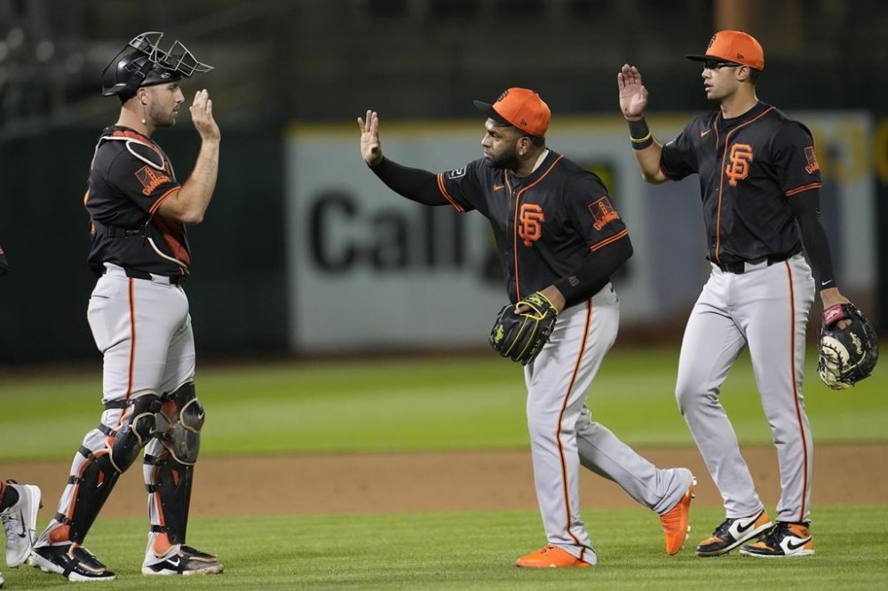 San Francisco Giants' Joey Bart, from left, celebrates with Pablo Sandoval and Blake Sabol after the Giants defeated the Oakland Athletics in a spring training baseball game in Oakland, Calif., Monday, March 25, 2024. (AP Photo/Jeff Chiu)
