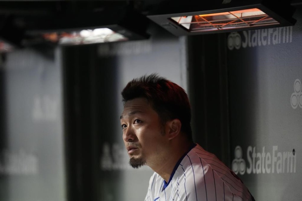 Chicago Cubs' Seiya Suzuki sits in the dugout under heat lamps during the second inning of the team's baseball game against the Colorado Rockies, Wednesday, April 3, 2024, in Chicago. (AP Photo/Erin Hooley)