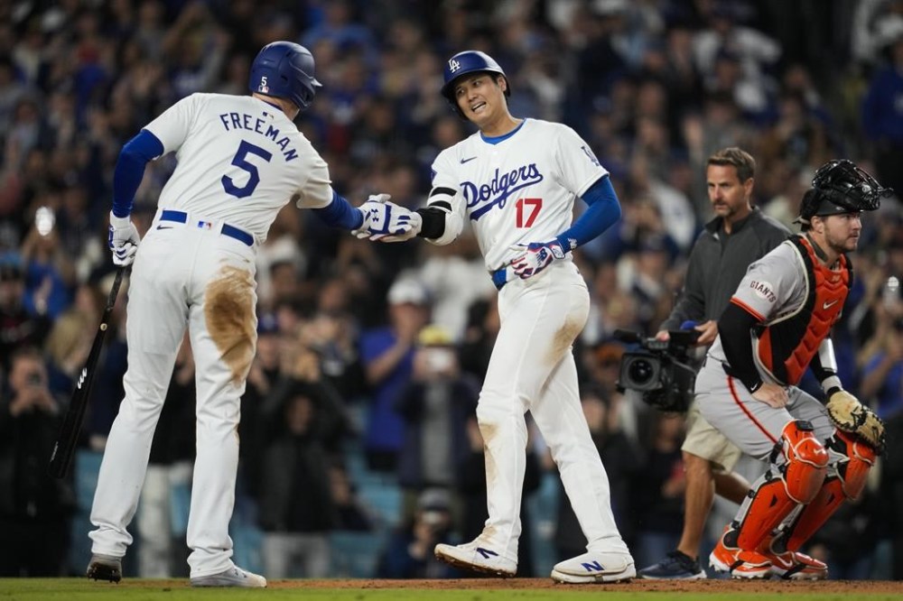 Los Angeles Dodgers designated hitter Shohei Ohtani celebrates with Freddie Freeman (5) after hitting a home run during the seventh inning of a baseball game against the San Francisco Giants in Los Angeles, Wednesday, April 3, 2024. (AP Photo/Ashley Landis)