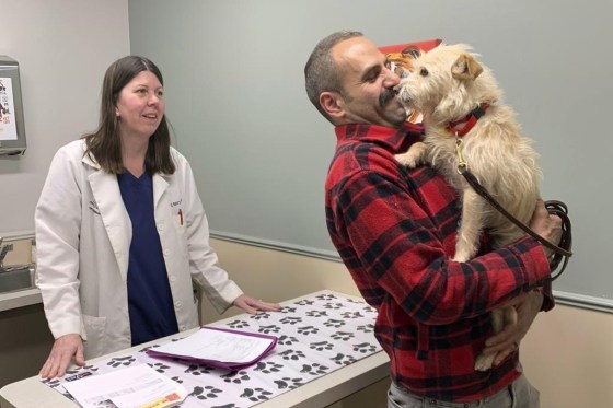 Mehrad Houman holds his dog, Mishka, after she was examined by veterinarian Nancy Pillsbury in Harper Woods, Mich., on March 29. (Corinne Martin via The Associated Press)