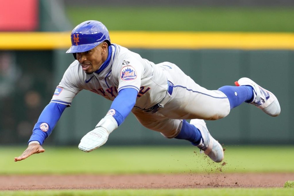 New York Mets' Francisco Lindor dives into third base on a single by Brett Baty against the Cincinnati Reds during the first inning of a baseball game Friday, April 5, 2024, in Cincinnati. (AP Photo/Jeff Dean)
