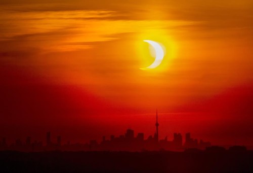 An annular solar eclipse rises over the skyline of Toronto on Thursday, June 10, 2021. A total solar eclipse is a rare celestial event that always generates excitement, but Monday's version is expected to be unusually spectacular. THE CANADIAN PRESS/Frank Gunn
