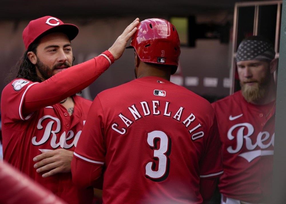 Cincinnati Reds' Jeimer Candelario (3) celebrates with Jonathan India, left, after scoring on a fielding error by New York Mets second baseman Jeff McNeil during the second inning of a baseball game Saturday, April 6, 2024, in Cincinnati. (AP Photo/Jeff Dean)