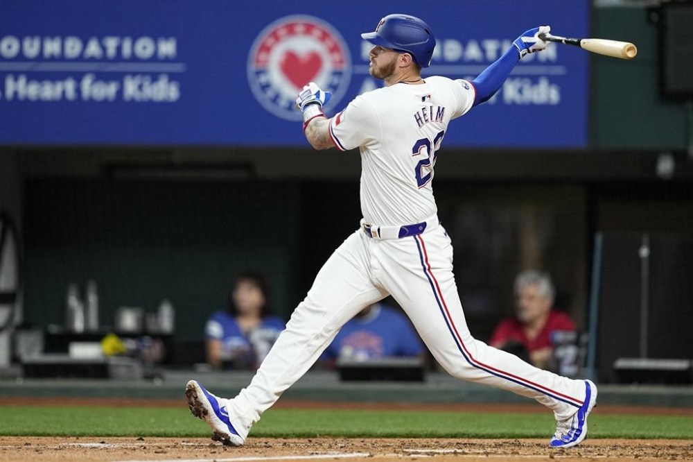 Texas Rangers' Jonah Heim follows through on an RBI single against the Houston Astros during the second inning of a baseball game in Arlington, Texas, Saturday, April 6, 2024. (AP Photo/Tony Gutierrez)