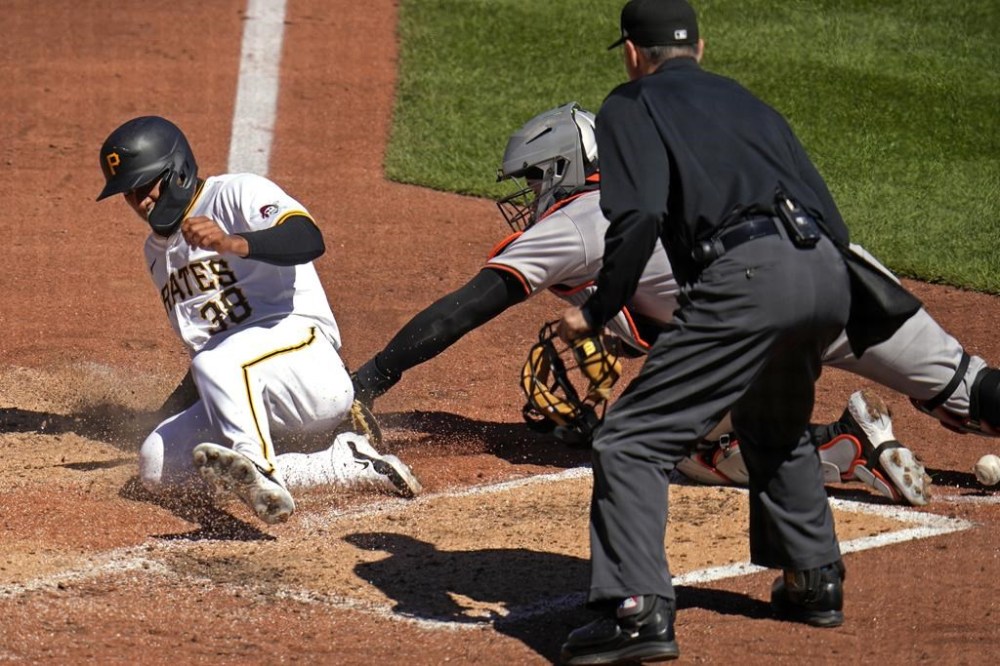 Pittsburgh Pirates' Edward Olivares (38) scores from third after tagging up on a sacrifice fly by Henry Davis as Baltimore Orioles catcher James McCann attempts a tag without the ball, during the fifth inning of a baseball game in Pittsburgh, Sunday, April 7, 2024. Making the call on the play is umpire Dan Lassogna. (AP Photo/Gene J. Puskar)